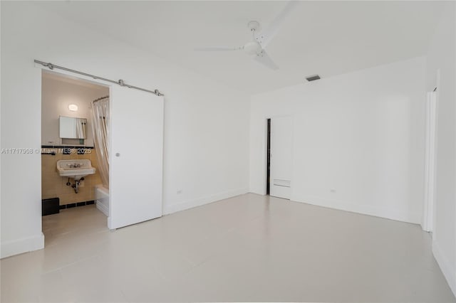 tiled spare room featuring sink, ceiling fan, and tile walls