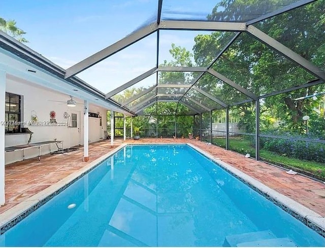 view of swimming pool featuring glass enclosure, ceiling fan, and a patio area