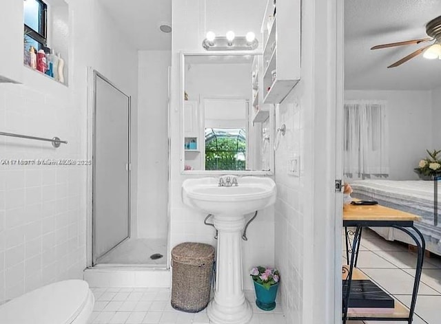 bathroom featuring tile patterned flooring, toilet, ceiling fan, and a shower with shower door