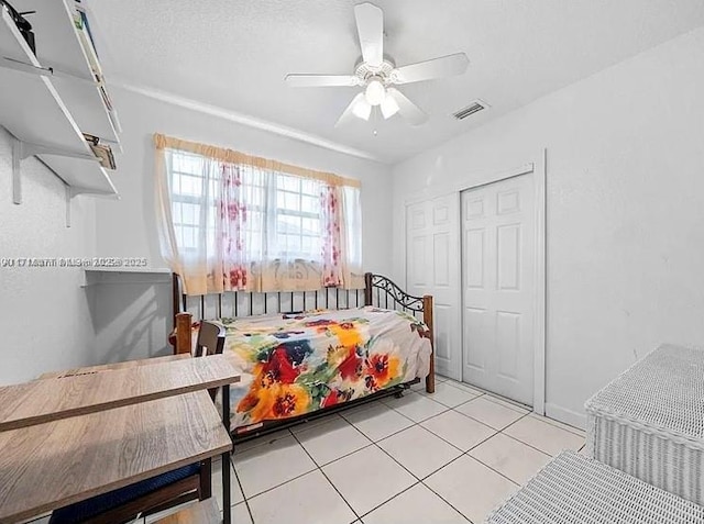 tiled bedroom featuring ceiling fan and a closet