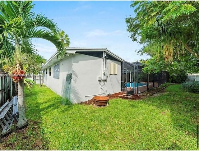 view of property exterior with a yard, a fenced in pool, and a lanai