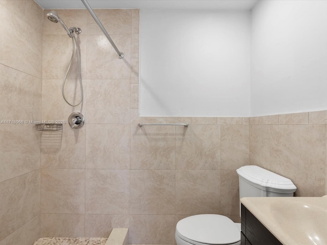 bathroom featuring vanity, toilet, tile walls, and a tile shower