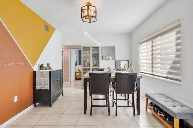 dining space featuring light tile patterned flooring and an inviting chandelier