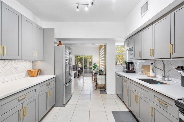 kitchen with tasteful backsplash, gray cabinets, sink, and stainless steel appliances