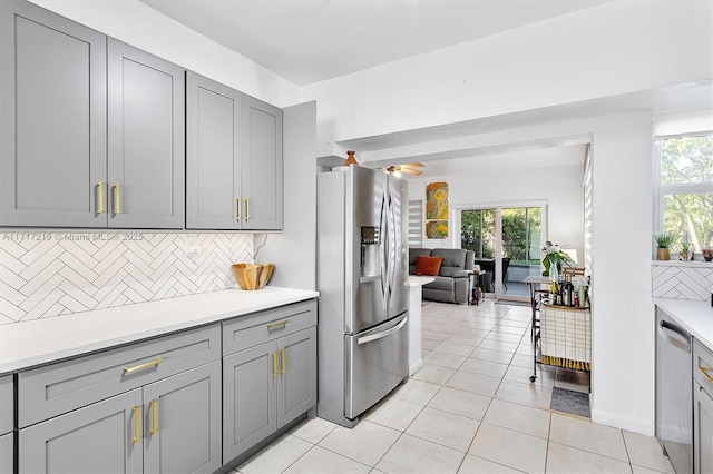 kitchen with backsplash, gray cabinets, light tile patterned flooring, and stainless steel appliances