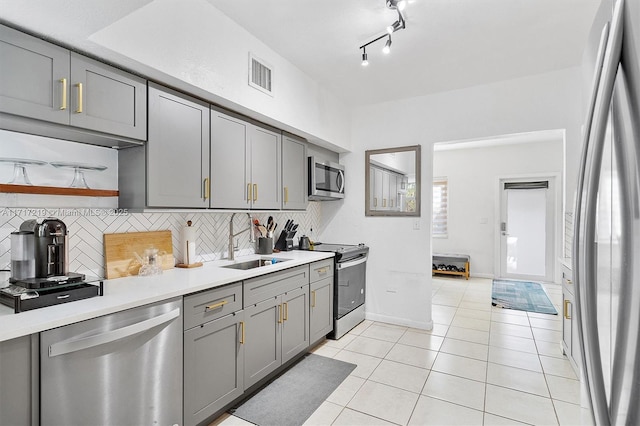 kitchen with tasteful backsplash, gray cabinetry, stainless steel appliances, sink, and light tile patterned flooring