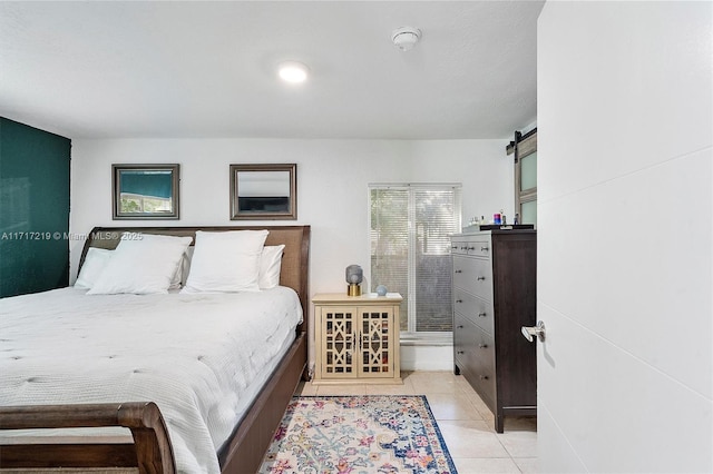 bedroom with a barn door and light tile patterned flooring