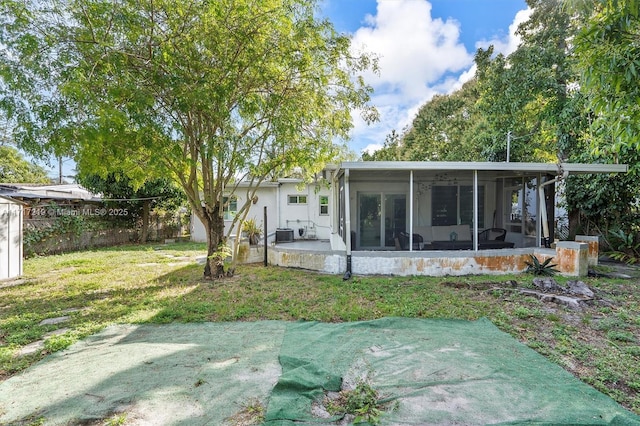 rear view of property featuring a yard, central air condition unit, and a sunroom