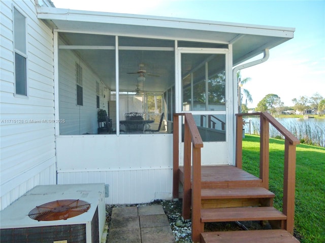 entrance to property featuring central air condition unit, a lawn, and a water view