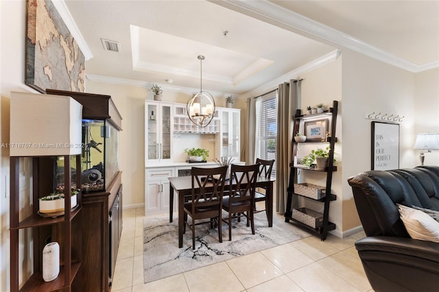 dining space with light tile patterned flooring, a raised ceiling, ornamental molding, and a chandelier