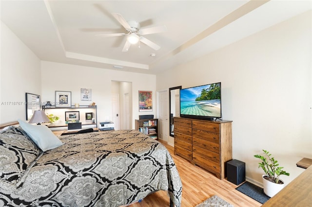 bedroom with a tray ceiling, ceiling fan, and hardwood / wood-style flooring