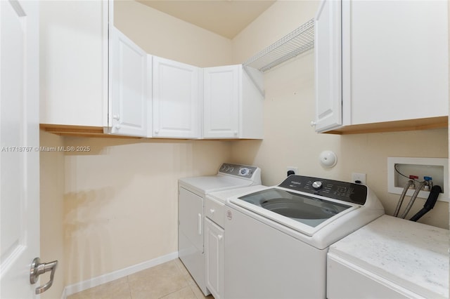 clothes washing area with washer and clothes dryer, cabinets, and light tile patterned floors