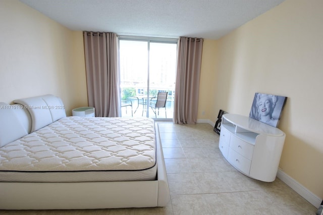 tiled bedroom featuring access to exterior, a textured ceiling, and a wall of windows