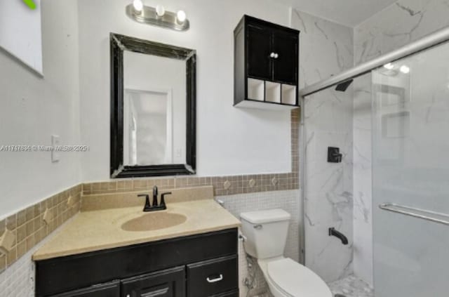 bathroom featuring vanity, a shower with shower door, tile walls, and toilet