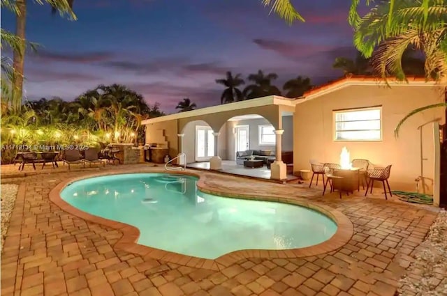 outdoor pool with french doors, a patio, and a fire pit