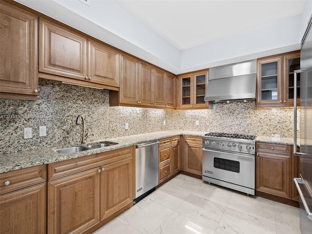 kitchen with wall chimney exhaust hood, high end appliances, decorative backsplash, and sink