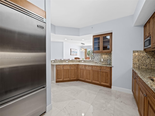 kitchen featuring backsplash, light stone counters, and stainless steel appliances