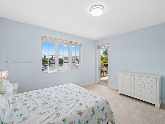 carpeted bedroom with access to exterior and a water view