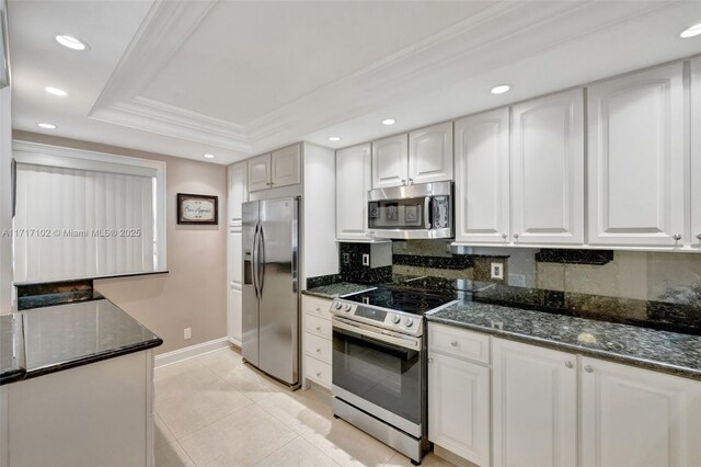 kitchen with dark stone counters, white cabinets, ornamental molding, and appliances with stainless steel finishes