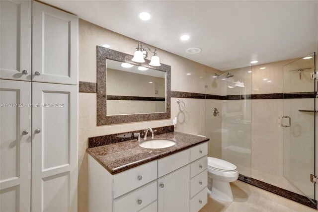 bathroom with vanity, tile walls, tile patterned flooring, toilet, and a shower with shower door