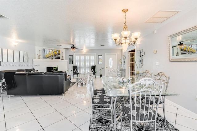 dining room featuring tile patterned floors, ceiling fan with notable chandelier, and a textured ceiling