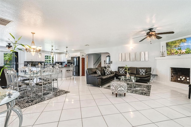 living room with ceiling fan with notable chandelier, light tile patterned floors, and a textured ceiling