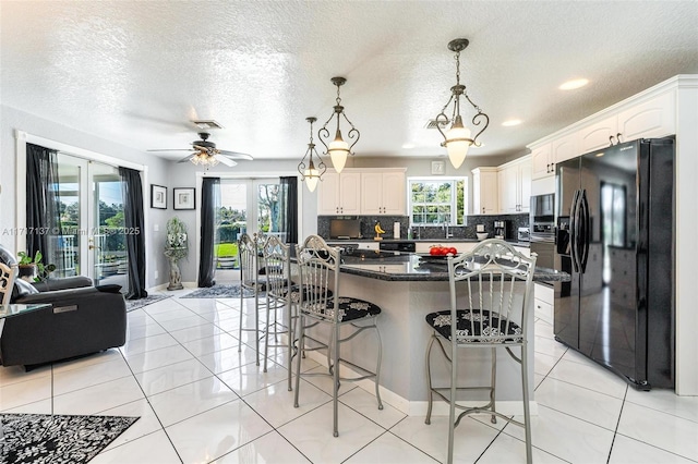 kitchen featuring a center island, french doors, hanging light fixtures, decorative backsplash, and black fridge with ice dispenser