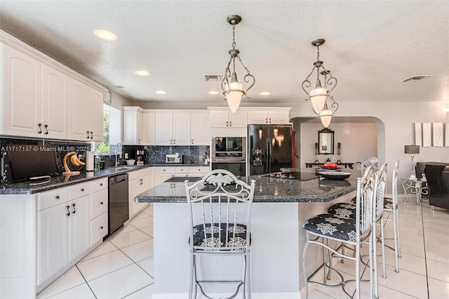 kitchen featuring a breakfast bar, white cabinets, black appliances, and a kitchen island