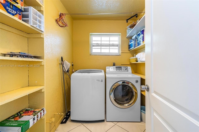 washroom with light tile patterned floors and washing machine and dryer