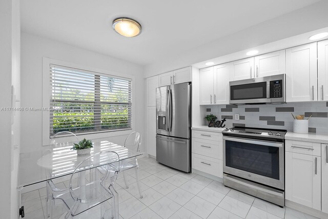 kitchen featuring stainless steel appliances, white cabinets, and decorative backsplash