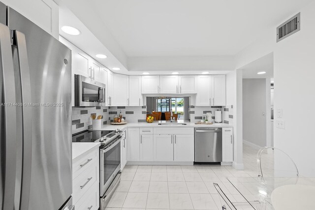 kitchen with appliances with stainless steel finishes, sink, white cabinets, and decorative backsplash