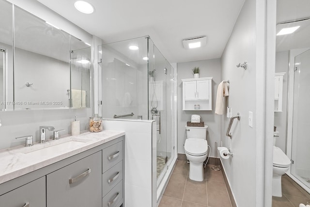 bathroom with vanity, toilet, a shower with door, and tile patterned flooring