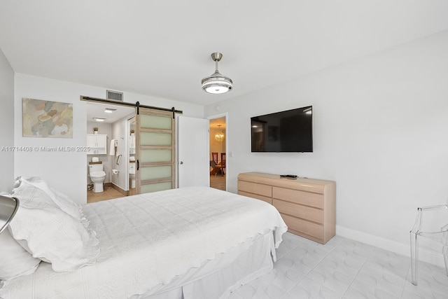 bedroom with a barn door and connected bathroom