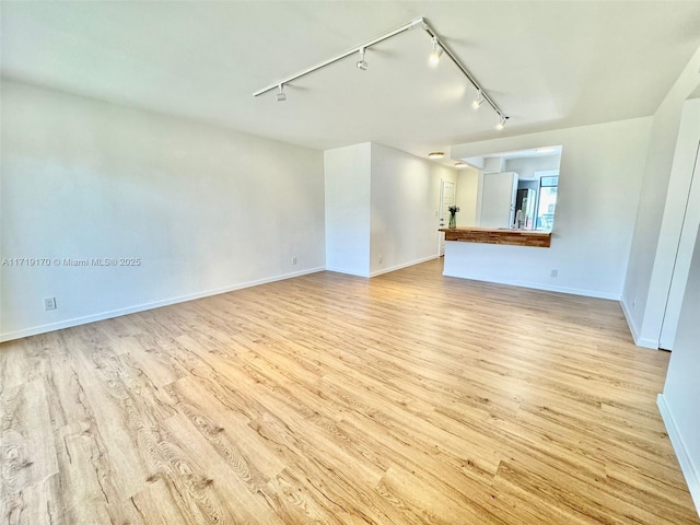 unfurnished living room with rail lighting and light hardwood / wood-style floors