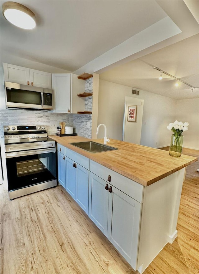 kitchen with wood counters, white cabinetry, sink, and appliances with stainless steel finishes