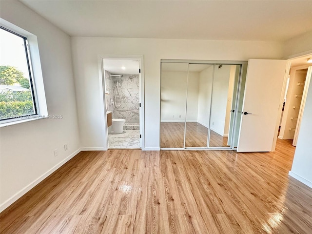 unfurnished bedroom featuring light hardwood / wood-style floors, a closet, and ensuite bath