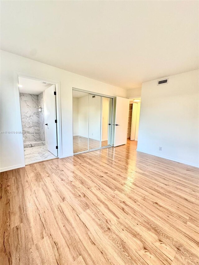 unfurnished bedroom featuring light wood-type flooring and ensuite bath