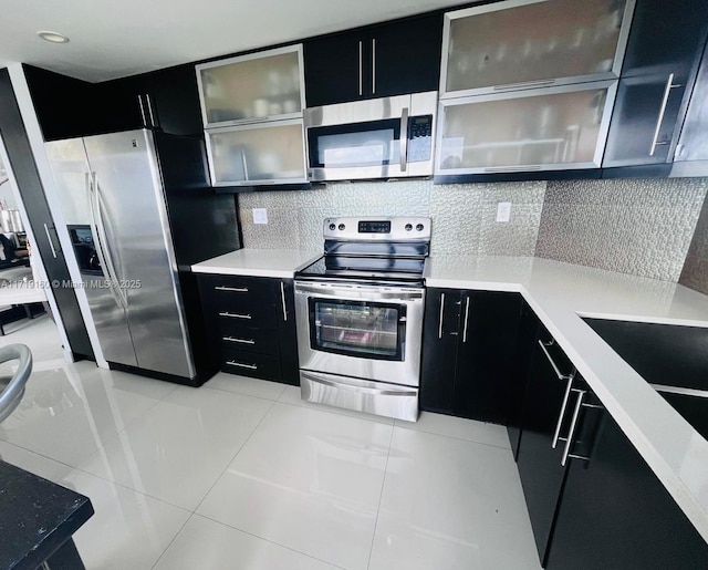 kitchen with appliances with stainless steel finishes, backsplash, and light tile patterned flooring