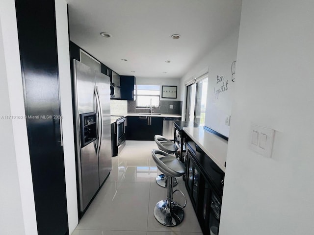 kitchen with decorative backsplash, light tile patterned floors, sink, and appliances with stainless steel finishes