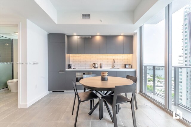 tiled dining area with floor to ceiling windows and sink