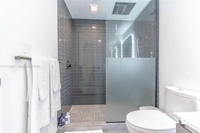 bathroom featuring tile patterned floors, toilet, vanity, and tiled shower