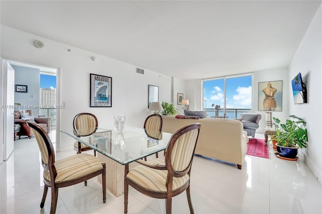 tiled dining area with a healthy amount of sunlight and a wall of windows