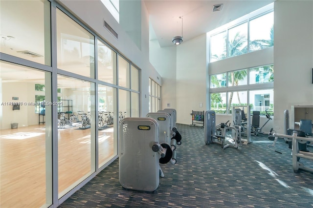 workout area with a high ceiling and dark carpet