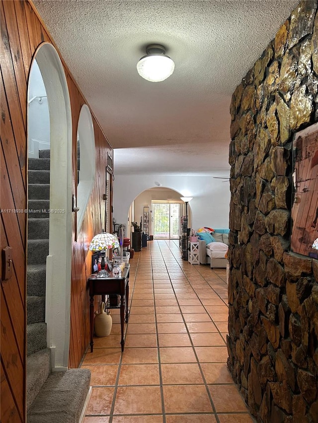 hallway with wooden walls and light tile patterned flooring