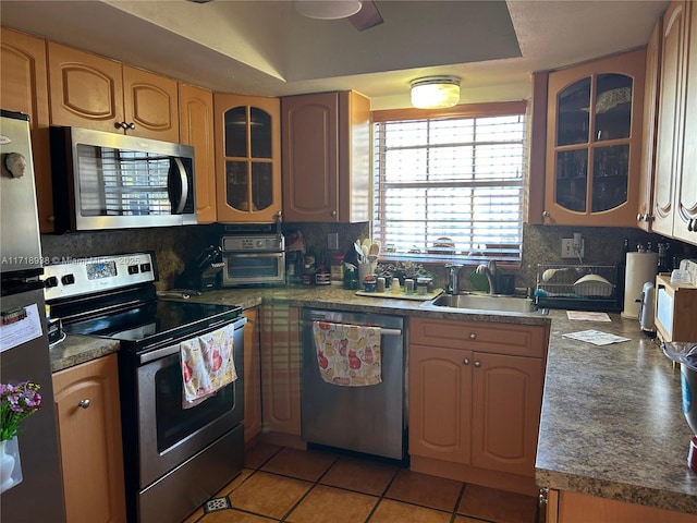 kitchen with sink, tasteful backsplash, light tile patterned floors, appliances with stainless steel finishes, and a tray ceiling