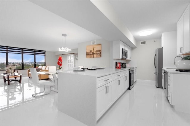 kitchen featuring white cabinets, appliances with stainless steel finishes, decorative light fixtures, and sink