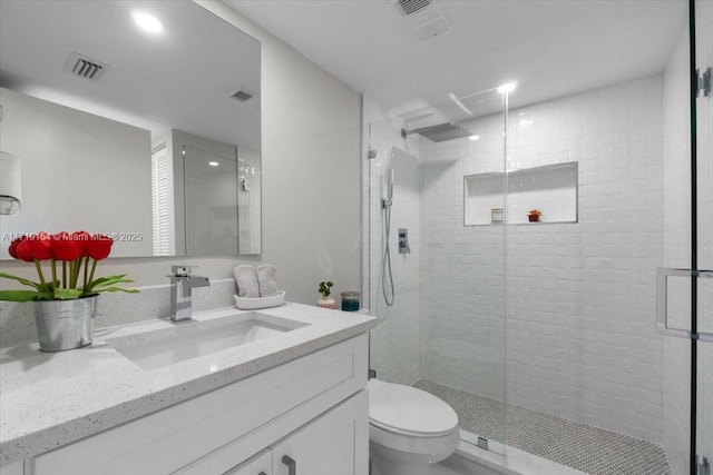 bathroom featuring a shower with door, vanity, and toilet