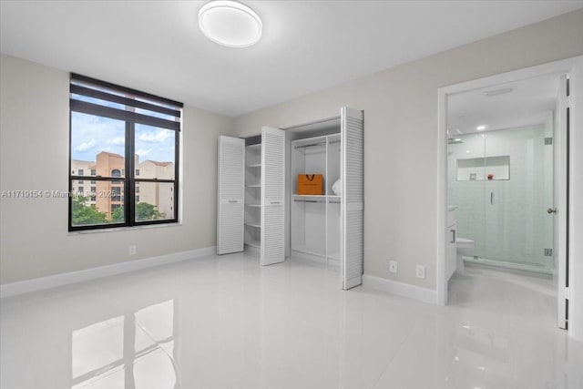 unfurnished bedroom featuring tile patterned flooring, ensuite bath, and a closet