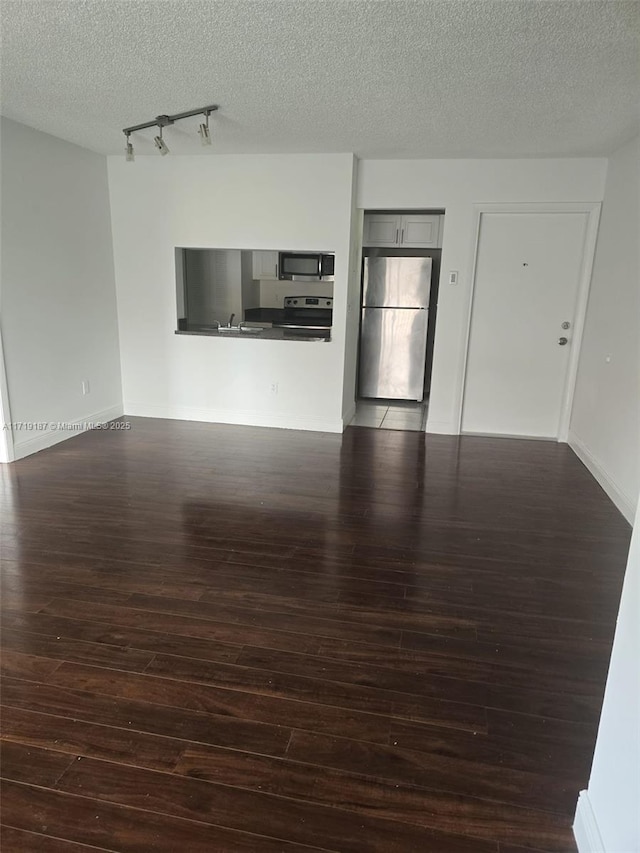 unfurnished living room with a textured ceiling, dark hardwood / wood-style flooring, and track lighting