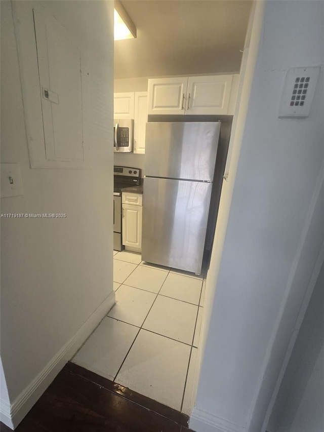 kitchen with electric panel, light tile patterned floors, white cabinetry, and appliances with stainless steel finishes